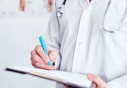 Médico escrevendo em prancheta durante avaliação